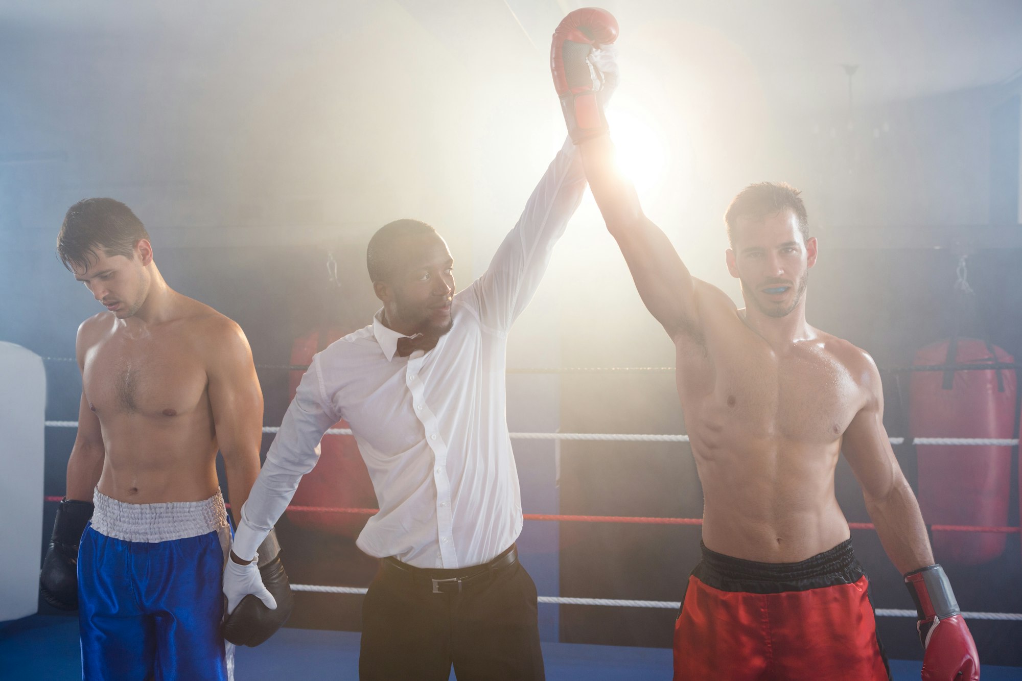 Referee lighting hand of winner in boxing ring